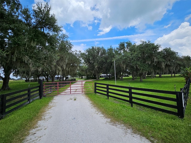 view of gate featuring a lawn and a rural view