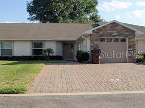 ranch-style house featuring an attached garage, a front lawn, and decorative driveway