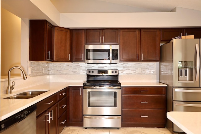 kitchen with a sink, marble finish floor, appliances with stainless steel finishes, and light countertops