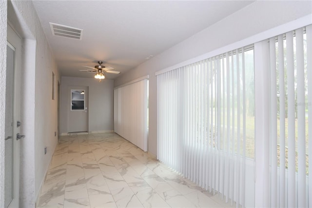 unfurnished room with visible vents, marble finish floor, plenty of natural light, and ceiling fan