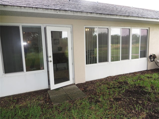 doorway to property with roof with shingles and stucco siding