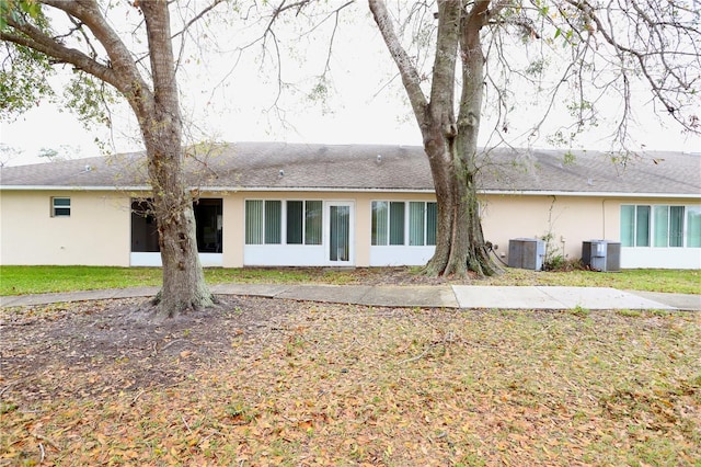 back of house featuring cooling unit, a yard, and stucco siding