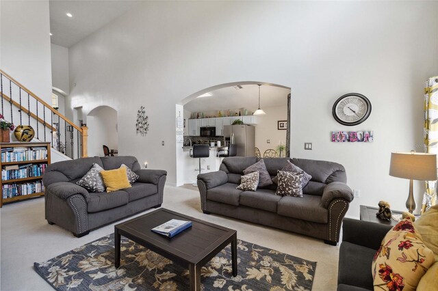 241 Grosvenor Loop, Davenport, FL 33897 - living area featuring arched walkways, light colored carpet, a towering ceiling, and stairs