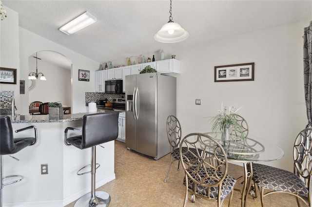 241 Grosvenor Loop, Davenport, FL 33897 - kitchen with appliances with stainless steel finishes, arched walkways, a breakfast bar, white cabinets, and lofted ceiling