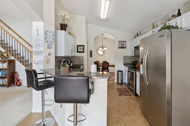 kitchen featuring a kitchen breakfast bar, appliances with stainless steel finishes, decorative backsplash, white cabinetry, and kitchen peninsula