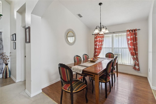 dining area featuring lofted ceiling, wood-type flooring, and a chandelier