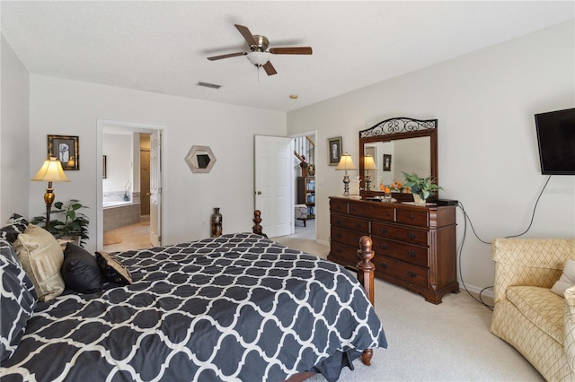 bedroom with a textured ceiling, ceiling fan, light carpet, and ensuite bathroom