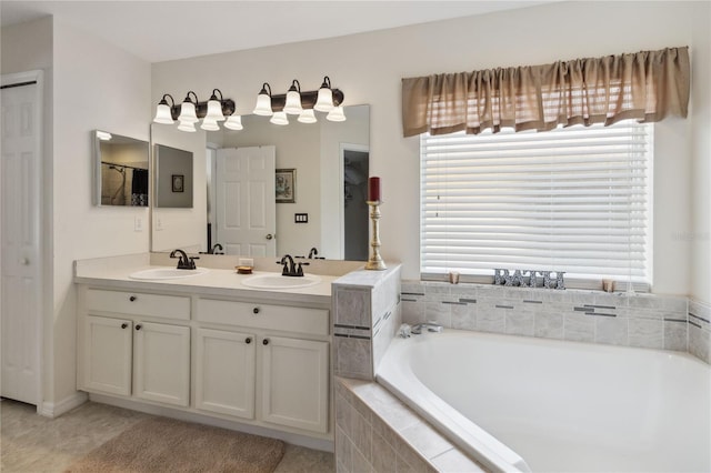 bathroom with tile patterned flooring, vanity, and tiled bath