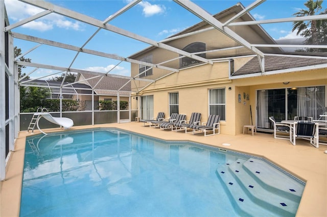 view of swimming pool with a water slide, a patio area, and a lanai