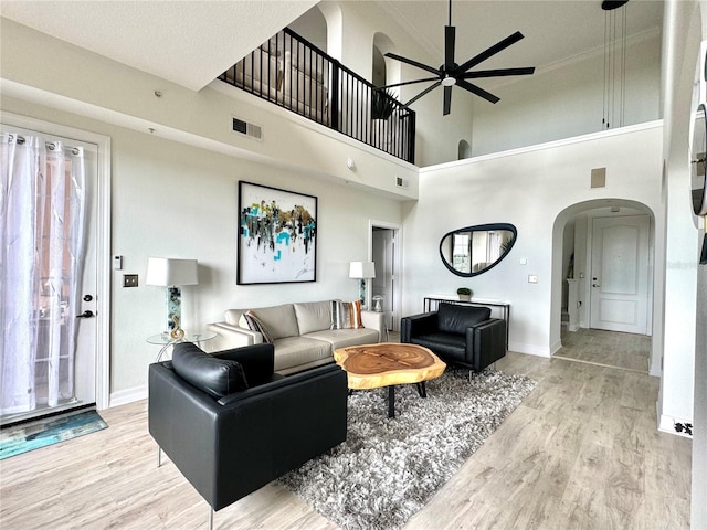 living room featuring a high ceiling, ceiling fan, and light wood-type flooring