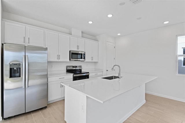 kitchen with a kitchen island with sink, sink, white cabinets, and appliances with stainless steel finishes