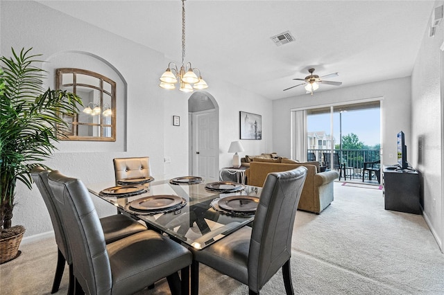 carpeted dining room with ceiling fan with notable chandelier