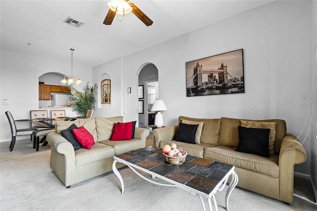 living room featuring carpet flooring and ceiling fan with notable chandelier