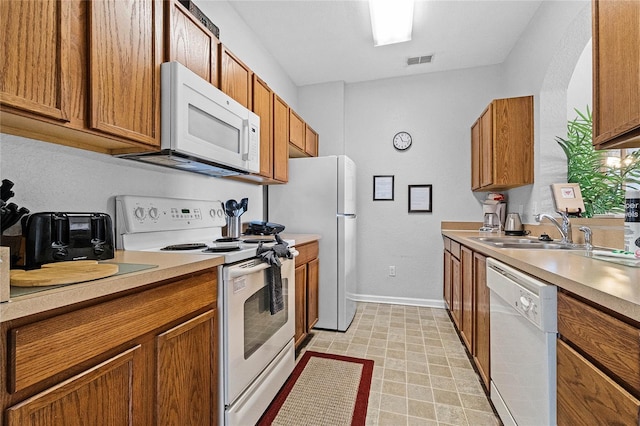 kitchen featuring light tile patterned flooring, sink, and white appliances