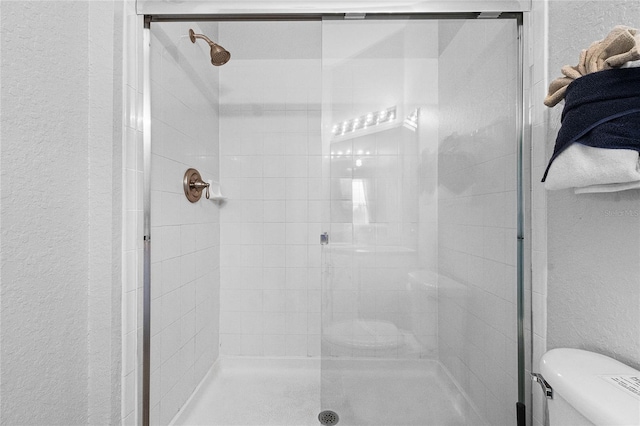 bathroom with a shower with door and toilet