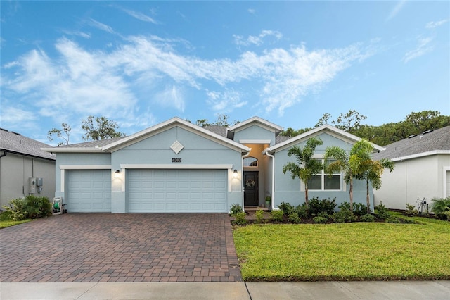 single story home featuring a front yard, decorative driveway, a garage, and stucco siding