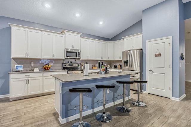 kitchen featuring stainless steel appliances, tasteful backsplash, a breakfast bar area, and wood tiled floor