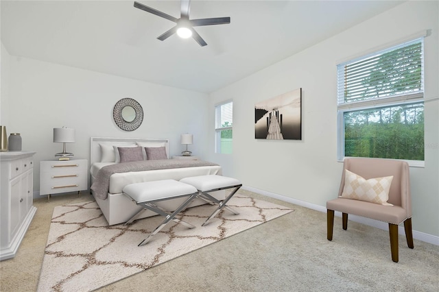 bedroom with a ceiling fan, light colored carpet, and baseboards