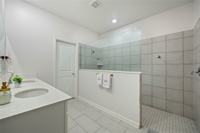 bathroom with tiled shower, tile patterned flooring, and vanity