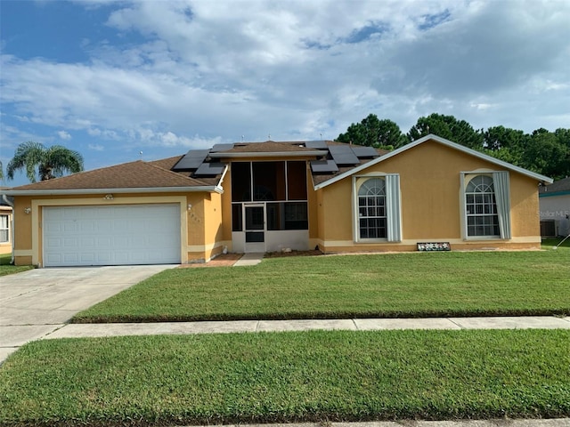 view of front facade featuring central AC unit, a front yard, solar panels, and a garage