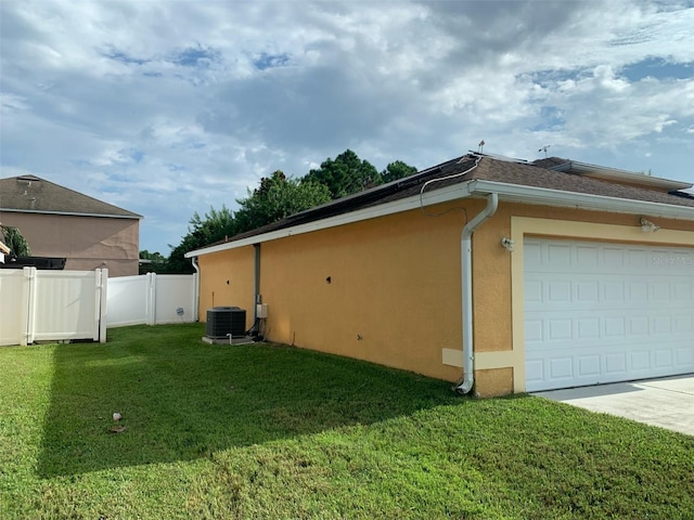 view of side of property featuring a garage, central AC unit, and a lawn