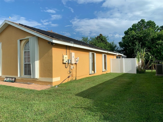 view of home's exterior featuring central air condition unit, a lawn, fence, and stucco siding