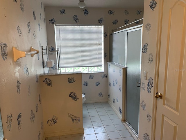 full bath with toilet, a stall shower, tile patterned flooring, and baseboards