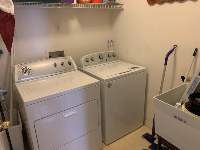 clothes washing area featuring sink, washing machine and clothes dryer, and light tile patterned flooring