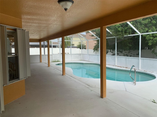 view of swimming pool with glass enclosure and a patio area