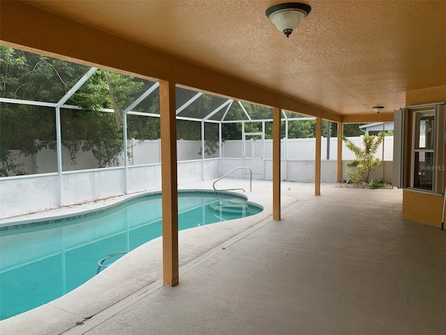 view of pool with glass enclosure and a patio