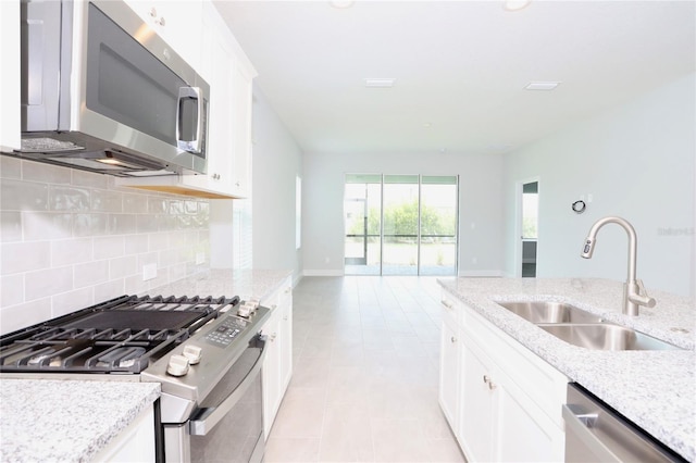 kitchen featuring light stone counters, stainless steel appliances, sink, and white cabinets