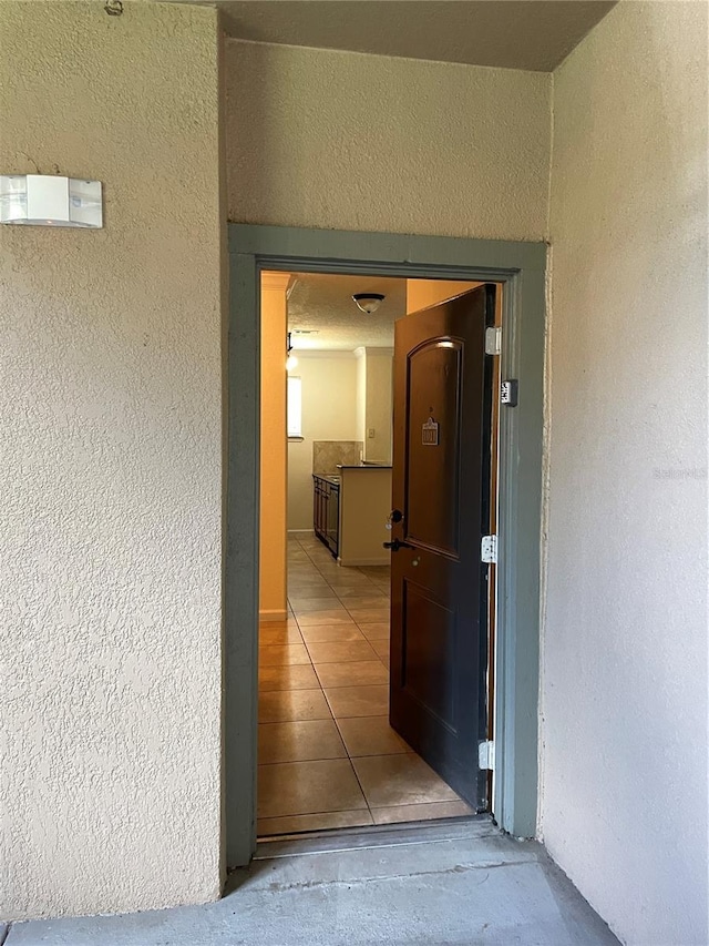 hall featuring a textured wall and tile patterned floors