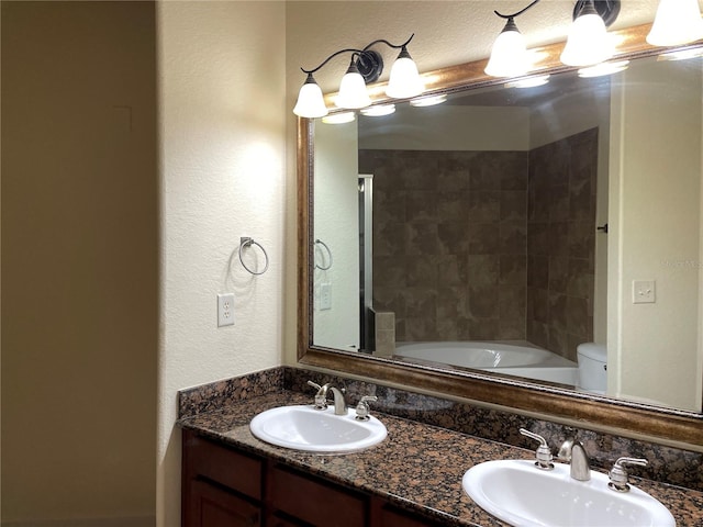 full bathroom featuring double vanity, tiled shower / bath, and toilet