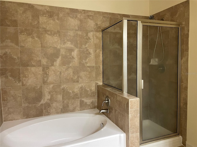 bathroom featuring a shower stall and a bath