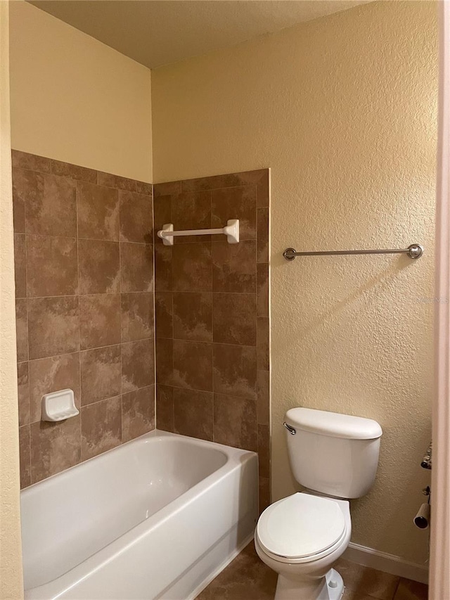 bathroom featuring tile patterned floors, tiled shower / bath, and toilet