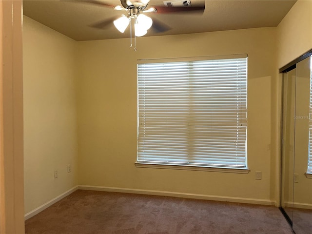 empty room with carpet floors, baseboards, and a ceiling fan