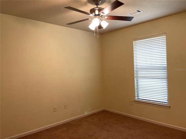 carpeted empty room featuring baseboards, a textured ceiling, visible vents, and a ceiling fan