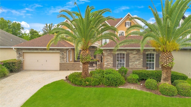 view of front facade with an attached garage, decorative driveway, and a front yard