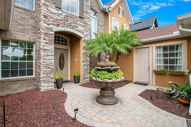 entrance to property featuring roof with shingles and stucco siding