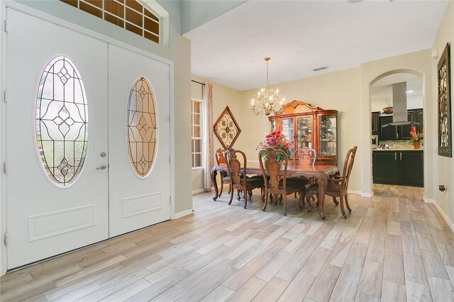 foyer featuring french doors, a chandelier, and light hardwood / wood-style flooring