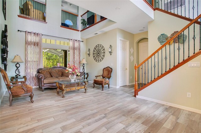 living room featuring light hardwood / wood-style floors and a towering ceiling