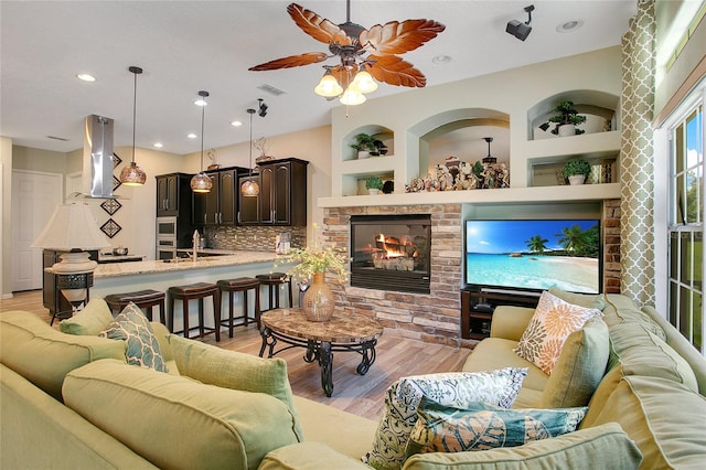 living room featuring built in features, ceiling fan, and light wood-type flooring