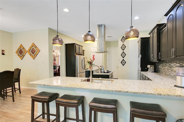 kitchen with stainless steel fridge with ice dispenser, a peninsula, a sink, island exhaust hood, and backsplash