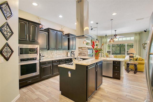 kitchen featuring island range hood, stainless steel appliances, open floor plan, tasteful backsplash, and an island with sink