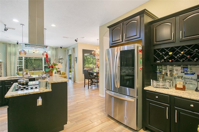 kitchen with a wealth of natural light, a kitchen island, stainless steel refrigerator, and light wood-type flooring