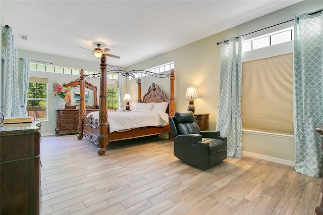 bedroom featuring light wood-type flooring, multiple windows, a textured ceiling, and ceiling fan