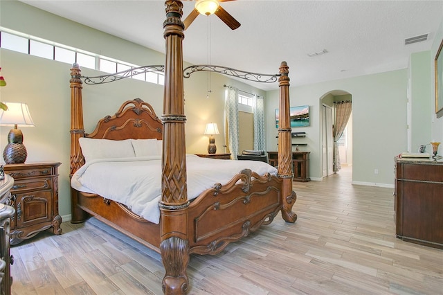 bedroom with arched walkways, baseboards, visible vents, and light wood finished floors