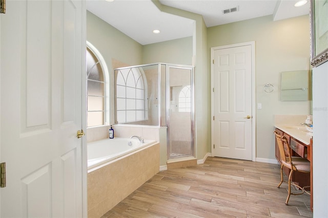 bathroom featuring hardwood / wood-style flooring, shower with separate bathtub, and vanity