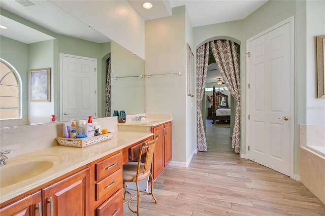 bathroom featuring vanity, hardwood / wood-style floors, and a relaxing tiled tub