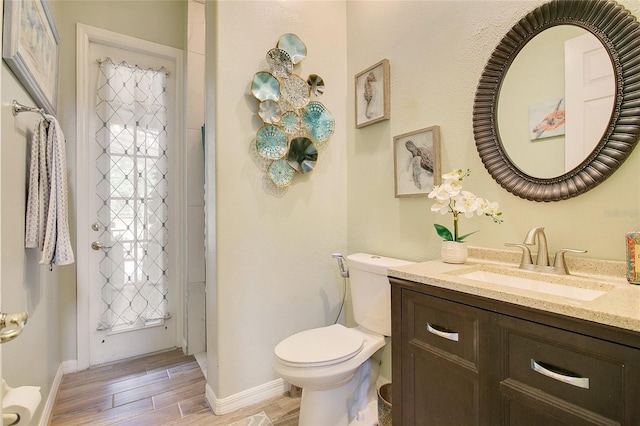 bathroom with baseboards, vanity, toilet, and wood tiled floor